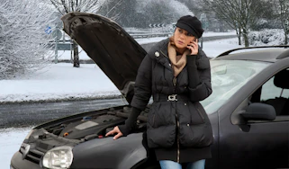 Woman on phone next to broken-down car