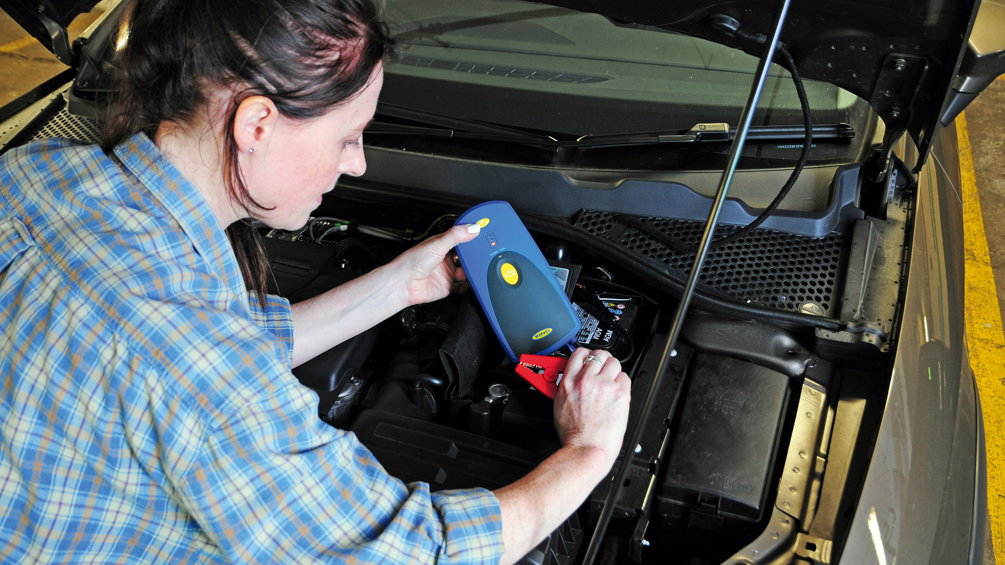 Woman checking the charge of a car battery
