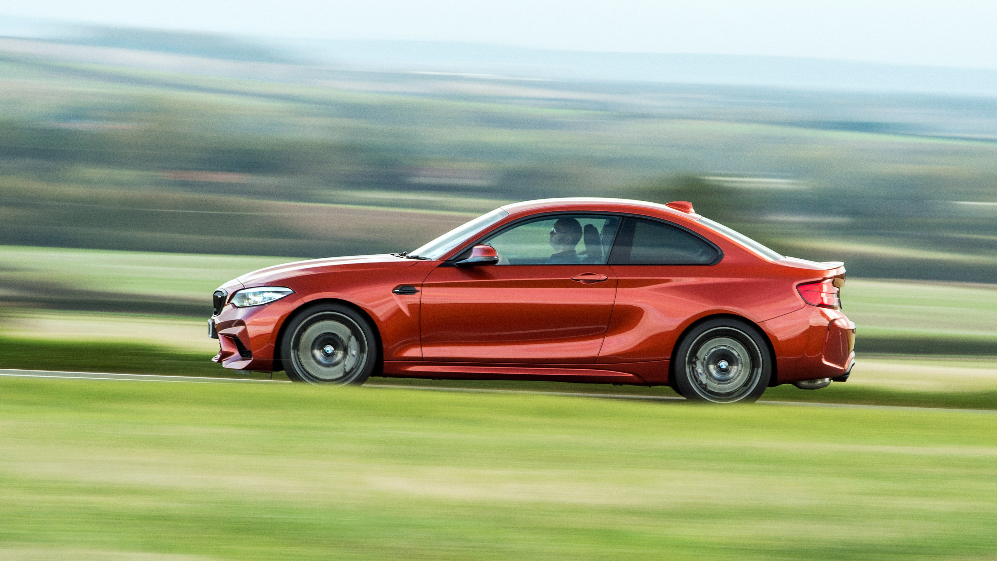 Orange BMW M2 driving - side view