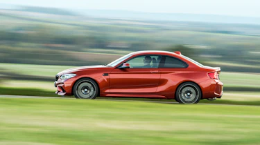 Orange BMW M2 driving - side view