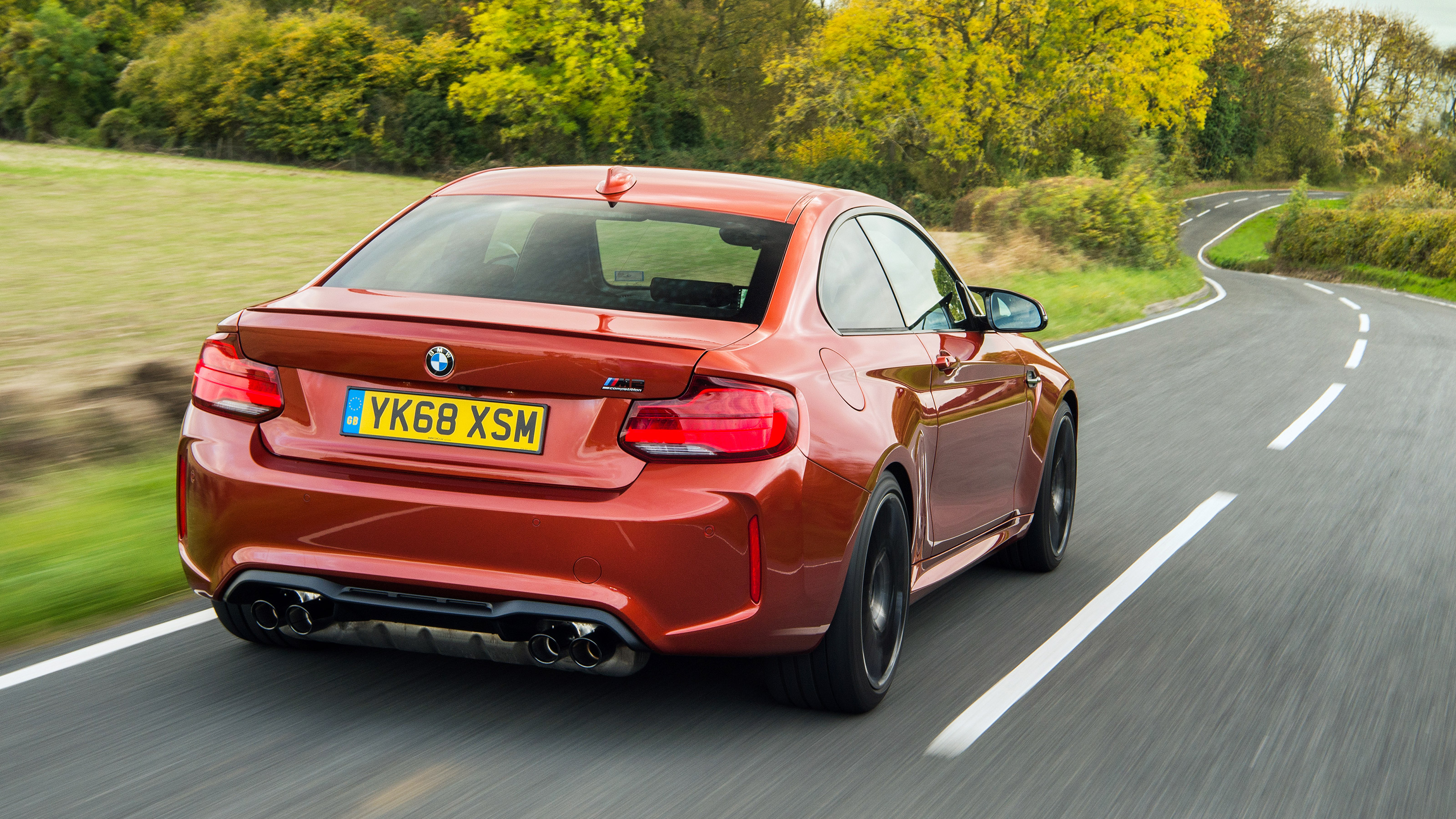 Orange BMW M2 driving - rear 