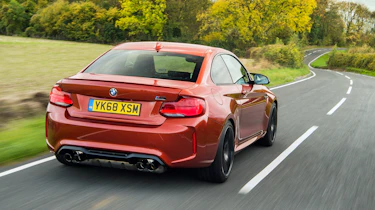 Orange BMW M2 driving - rear